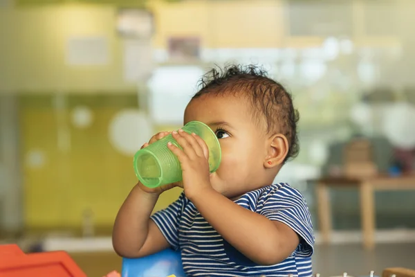 Feliz bebê bebendo água e brincando . — Fotografia de Stock