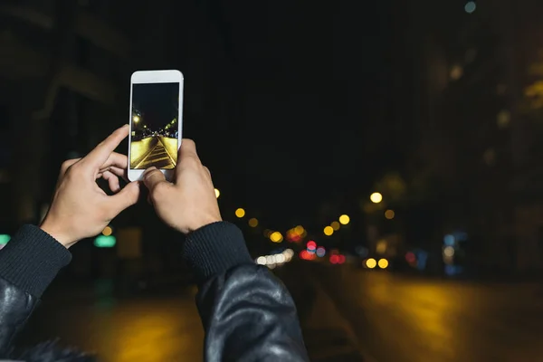 Boy takes a photograph of a street at night. — Stock Photo, Image