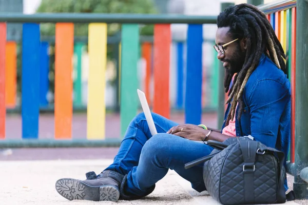 Портрет африканца, сидящего снаружи с ноутбуком . — стоковое фото