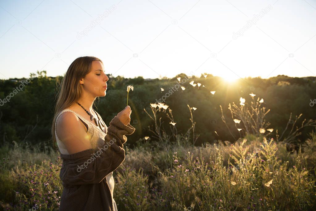 Woman blowing on a dandelion in the park.