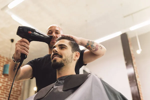 Hairstylist making men's haircut to an attractive man. — Stock Photo, Image