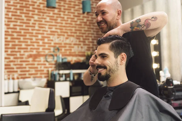 Haarstylist mannen kapsel aanbrengt een aantrekkelijke man. — Stockfoto