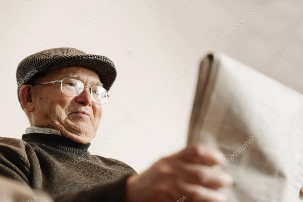 Elderly man reading a newspaper.