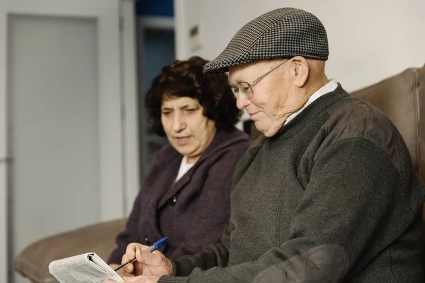 Elderly couple reading a newspaper. — Stock Photo, Image