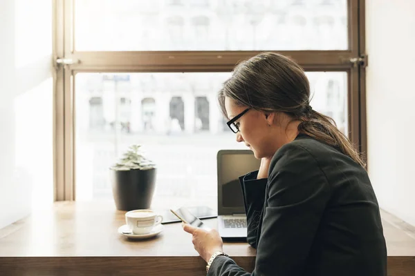 Empresaria usando su laptop y móvil en la Cafetería . — Foto de Stock