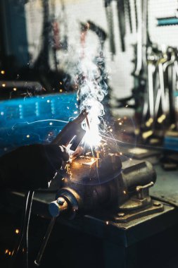 Tamirci adam garajında metal malzeme kaynak.