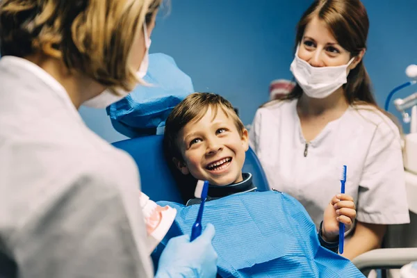 Médico dentista ensinando uma criança a escovar os dentes . — Fotografia de Stock