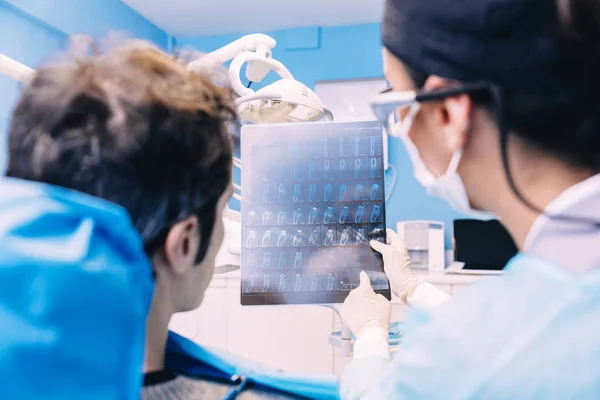 Dokter praat met haar patiënt en het onderwijzen van een radiografie. — Stockfoto