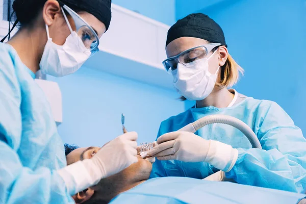 Dentists with a patient during a dental intervention. Royalty Free Stock Photos