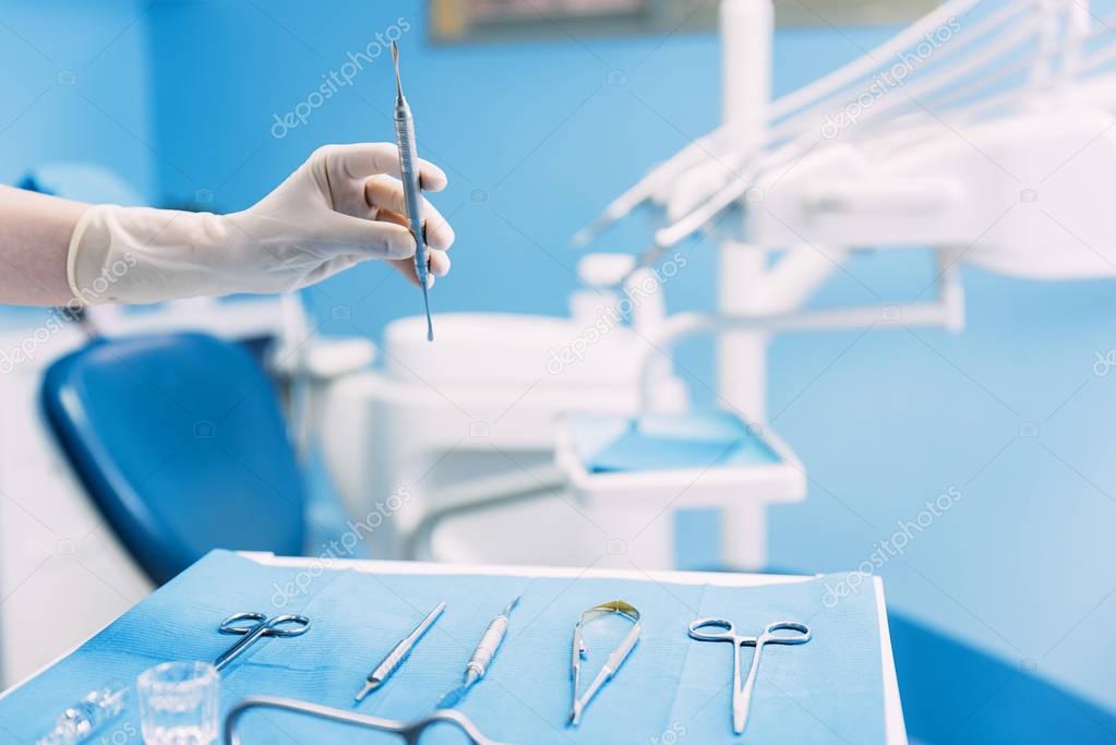 Detail of hand holding dental tools in dental clinic.