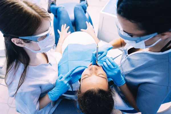 Dentistas con un paciente durante una intervención dental . — Foto de Stock