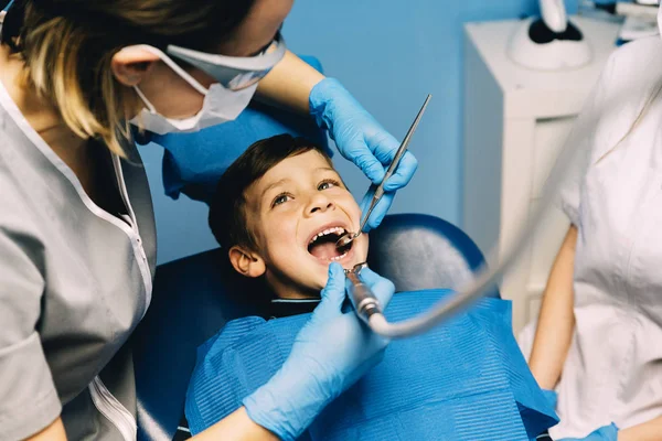 Dentistes avec un patient lors d'une intervention dentaire chez un garçon . — Photo