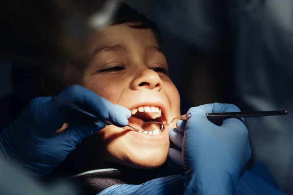 Zahnärzte mit einem Patienten während eines zahnärztlichen Eingriffs an Jungen. — Stockfoto