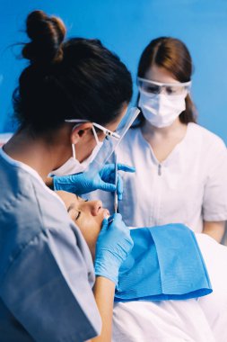 Diş hekimleri diş bir müdahale sırasında bir hastayla.