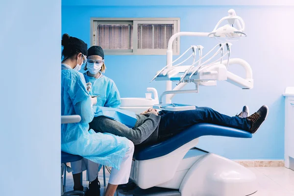 Dentistas con un paciente durante una intervención dental . — Foto de Stock