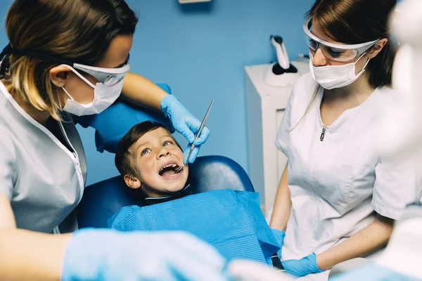 Dentistes avec un patient lors d'une intervention dentaire chez un garçon . — Photo