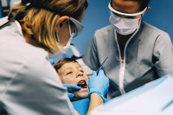 Стоматологи с пациентом во время стоматологического вмешательства к мальчику . — стоковое фото