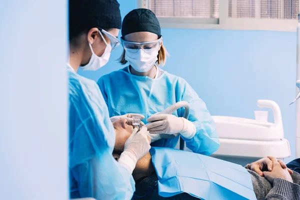 Dentists with a patient during a dental intervention. — Stock Photo, Image