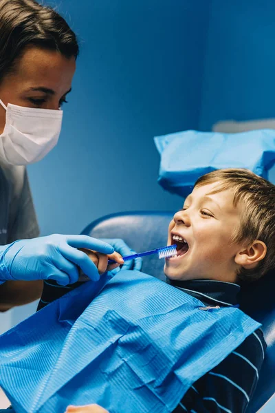 Zahnarzt bringt Kind das Zähneputzen bei. — Stockfoto