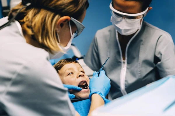 Стоматологи с пациентом во время стоматологического вмешательства к мальчику . — стоковое фото