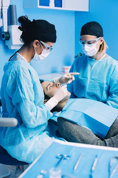 Dentistas con un paciente durante una intervención dental . — Foto de Stock