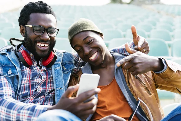 Dois amigos de raça negra se divertindo com celular . — Fotografia de Stock