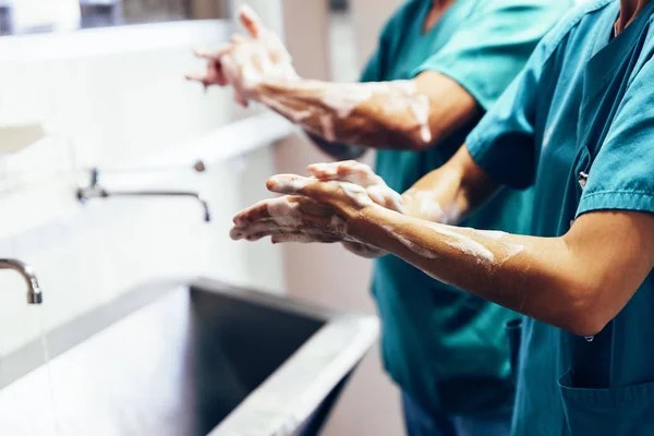 Casal de cirurgiões lavando as mãos antes de operar . — Fotografia de Stock