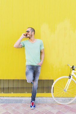 Yakışıklı genç adam cep telefonu ve sabit vites bisiklet.