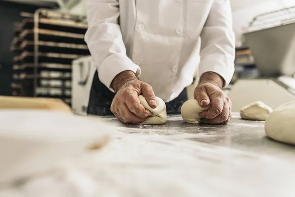 Пекарь смешивает тесто в пекарне. — стоковое фото