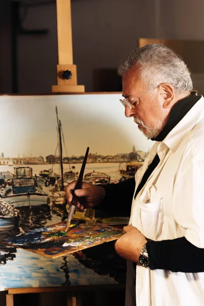 Vieil homme artiste peinture à l'huile dans son atelier . — Photo