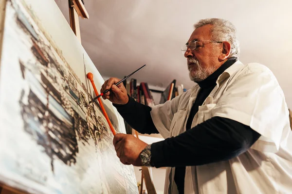 Vieil homme artiste peinture à l'huile dans son atelier . — Photo