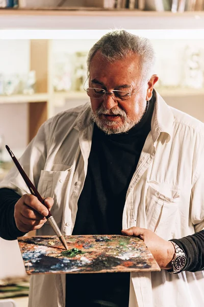Viejo artista pintando óleos en su estudio . —  Fotos de Stock