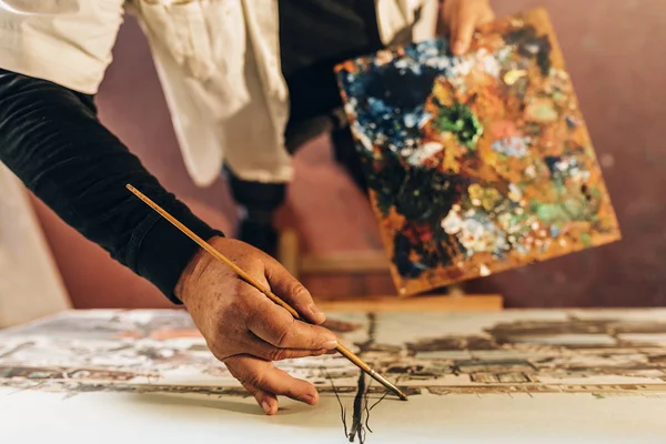 Old man artist painting oils in his studio. — Stock Photo, Image