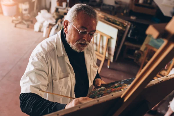 Viejo artista pintando óleos en su estudio . —  Fotos de Stock