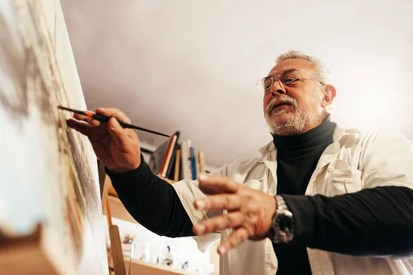 Vieil homme artiste peinture à l'huile dans son atelier . — Photo