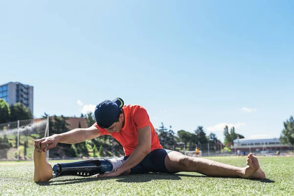 Atleta hombre discapacitado estiramiento con prótesis de pierna . — Foto de Stock