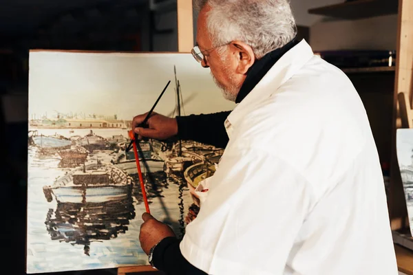 Vieil homme artiste peinture à l'huile dans son atelier . — Photo