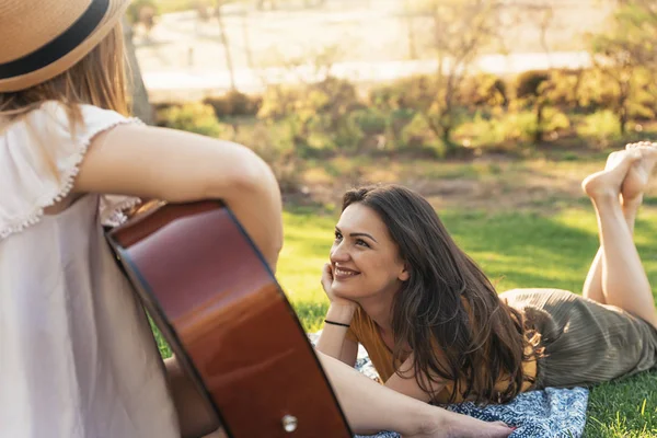 Mulheres bonitas se divertindo tocando guitarra no parque . — Fotografia de Stock