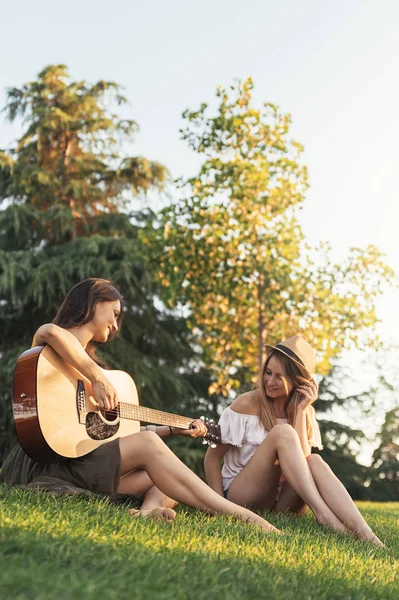 Mulheres bonitas se divertindo tocando guitarra no parque . — Fotografia de Stock