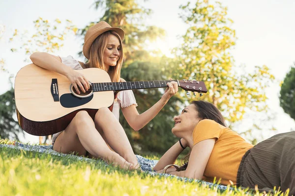 Krásné ženy, které baví hrát na kytaru v parku. — Stock fotografie