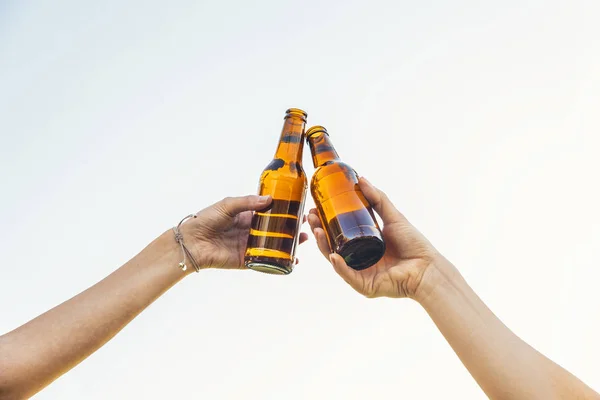 Female friends cheers clinking bottles of beer. — Stock Photo, Image