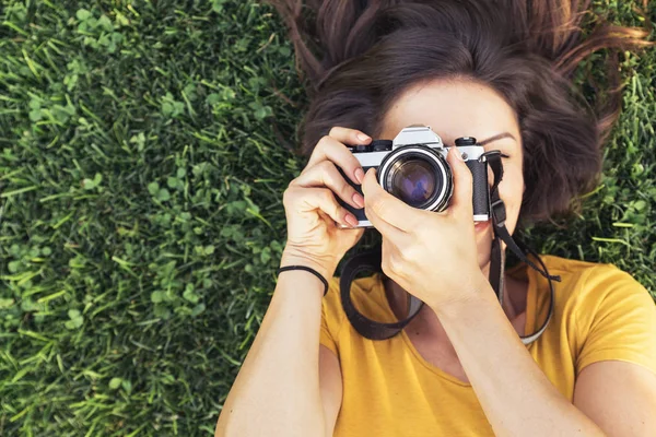 Mujer joven sonriente usando una cámara para tomar fotos. — Foto de Stock