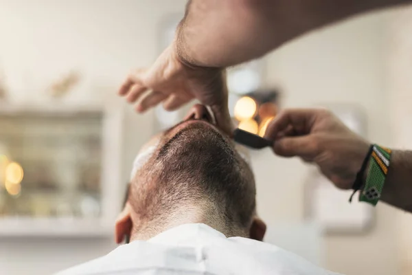 Junger bärtiger Mann bekommt vom Friseur eine Bartfrisur mit Rasiermesser. — Stockfoto