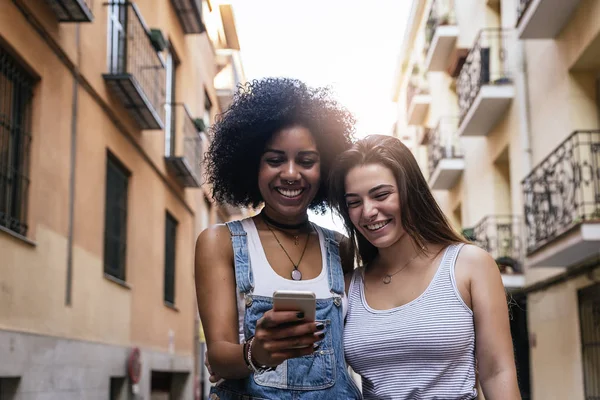 Mulheres bonitas usando um celular na rua. — Fotografia de Stock