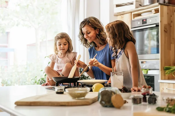 Hermanitas cocinando con su madre en la cocina . — Foto de Stock