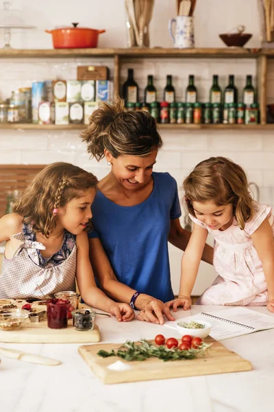 Hermanitas cocinando con su madre en la cocina . — Foto de Stock