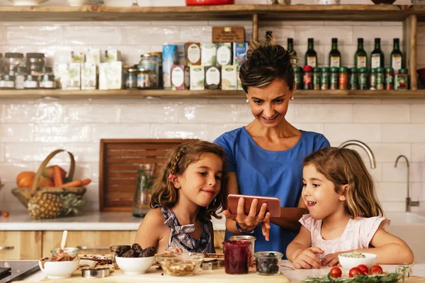 Hermanitas cocinando con su madre en la cocina . — Foto de Stock