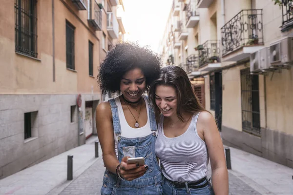 Mulheres bonitas usando um celular na rua. — Fotografia de Stock