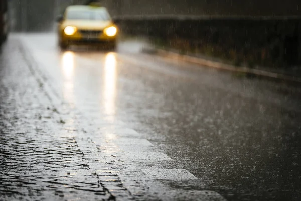 Táxi que circula no asfalto molhado enquanto chove . — Fotografia de Stock