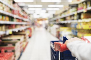 Kadının süpermarkette alışveriş sepeti kullanarak kapatın. Arka plan